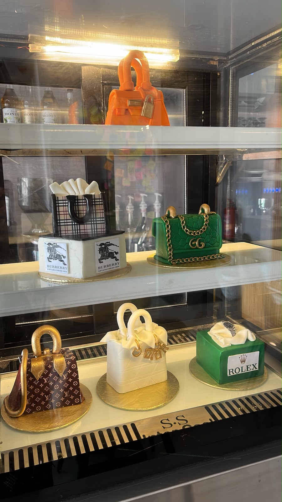 Designer handbag cakes lined up inside the café chiller display
